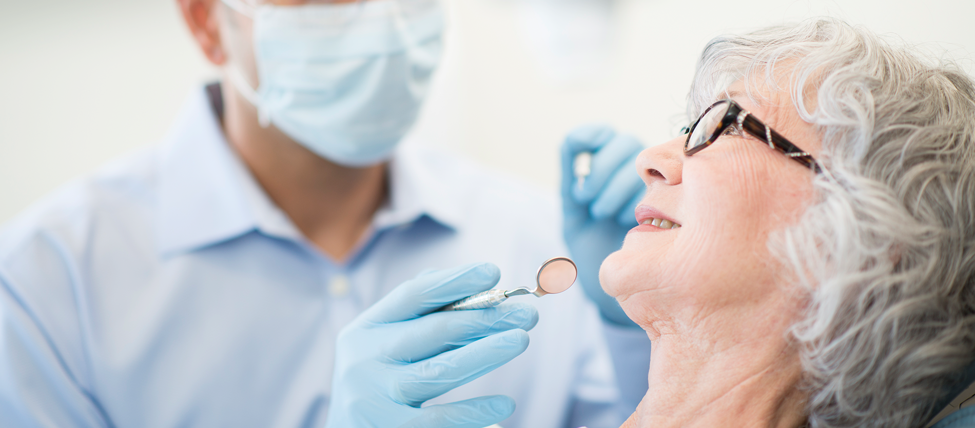 Dentist whitening an older woman's teeth